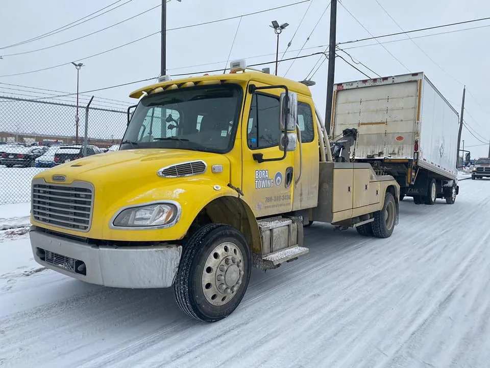 Bora Towing yellow wrecker towing a semi-trailer in winter Edmonton